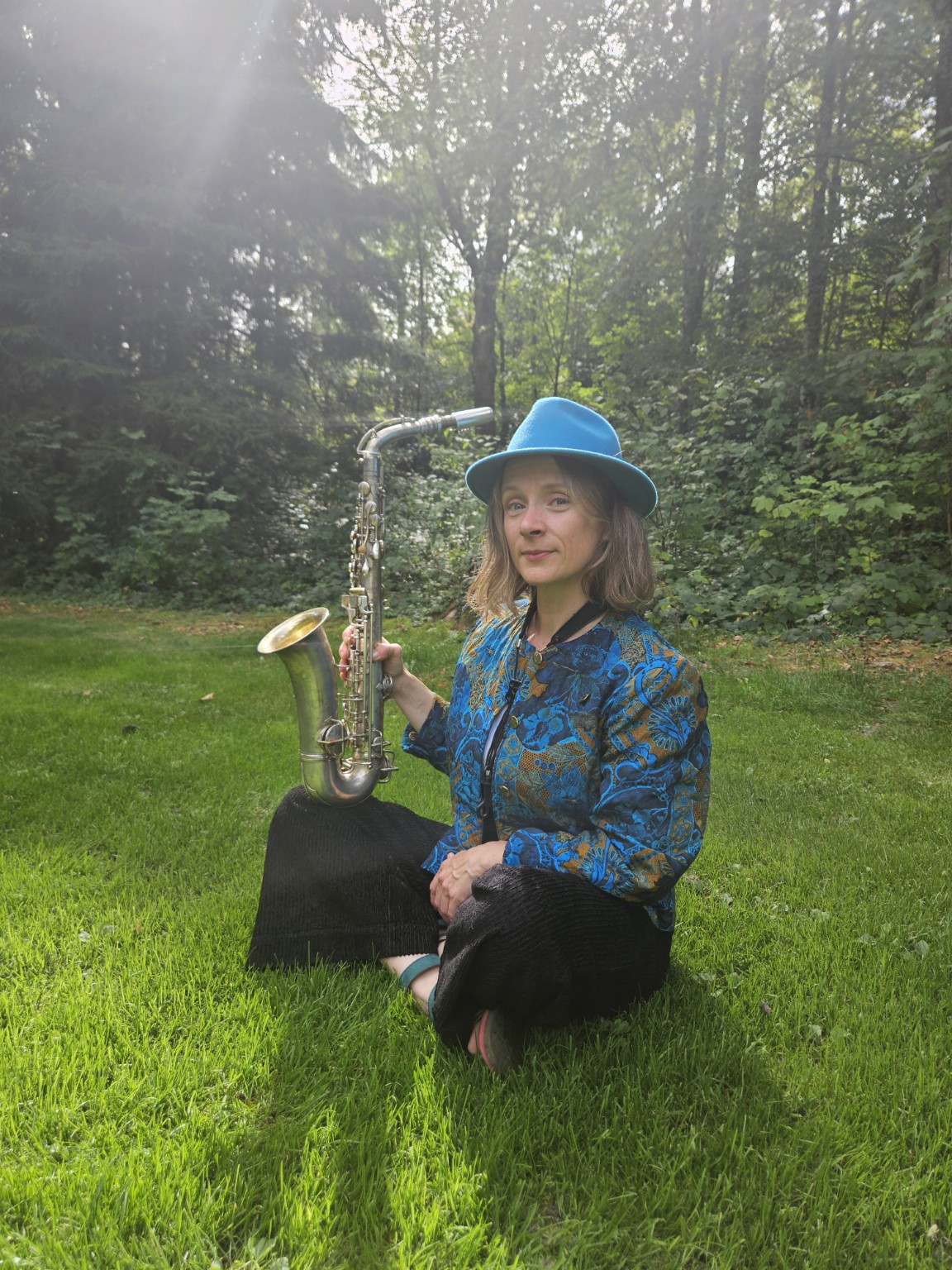 Stefanie Grass sitzt mit ihrem Saxophon im Grünen